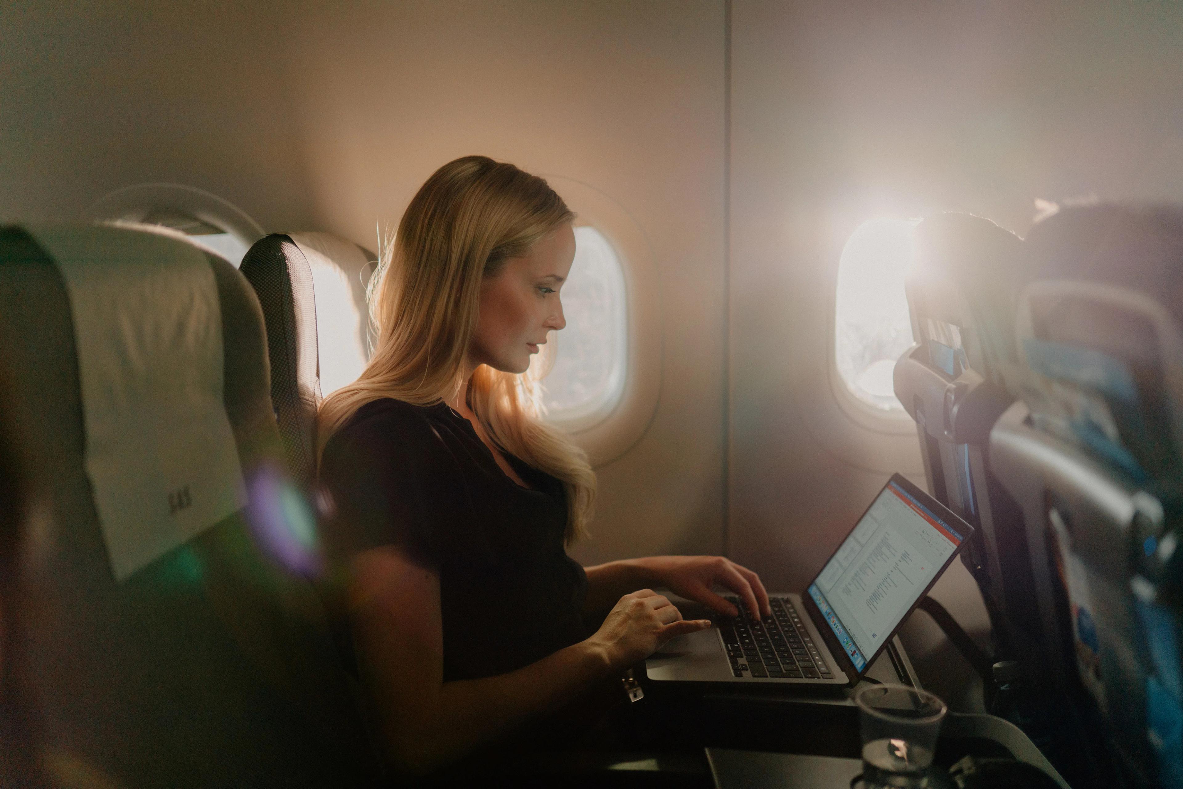 機内でWiFiを利用する女性旅行者